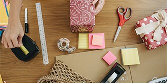 Femme emballant un cadeau avec des ciseaux, un dévidoir et un ruban végétal Scotch® Magic™
