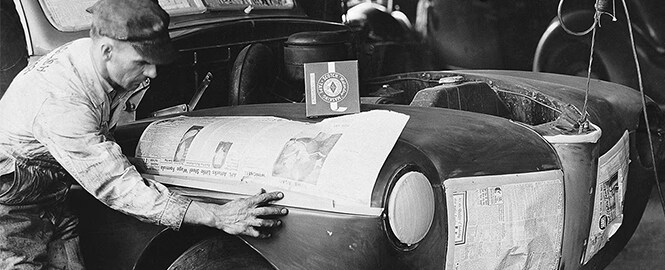 Image en noir et blanc d’un homme avec du ruban de masquage pour peindre une carrosserie

